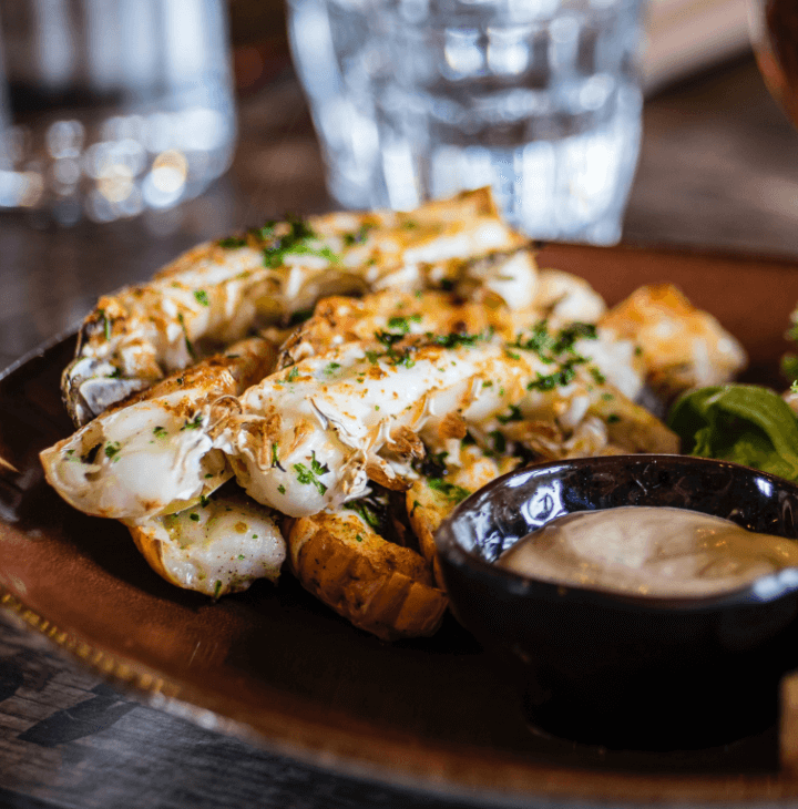 A plate of beautifully-spiced seafood with greens and a sipping sauce.